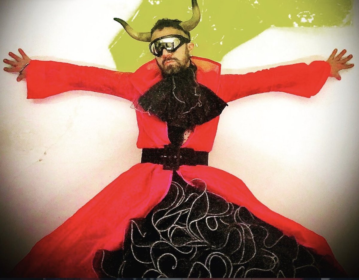 Retrato de estudio de Cabaret Silencio con kimono rojo, cuernos y falda negra bordada, sobre un fondo blanco con una mancha verde lima.